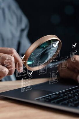 Opened laptop. Person holds magnifying glass in hand and scans a hologram with it.