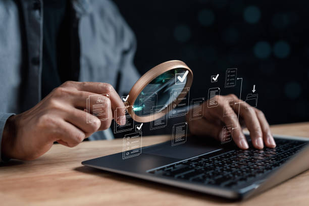 run-off Opened laptop. Person holds magnifying glass in hand and scans a hologram with it.