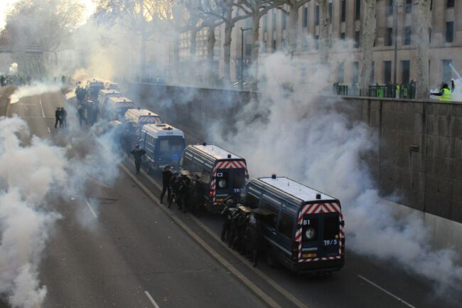smoke_street Black buses with security personnel are parked in a row on the street. Smoke rises from everywhere.